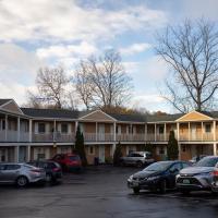 Fall or winter scene with two-story tan motel with cars parked in front.  Blue sky with white clouds and trees with no leaves.