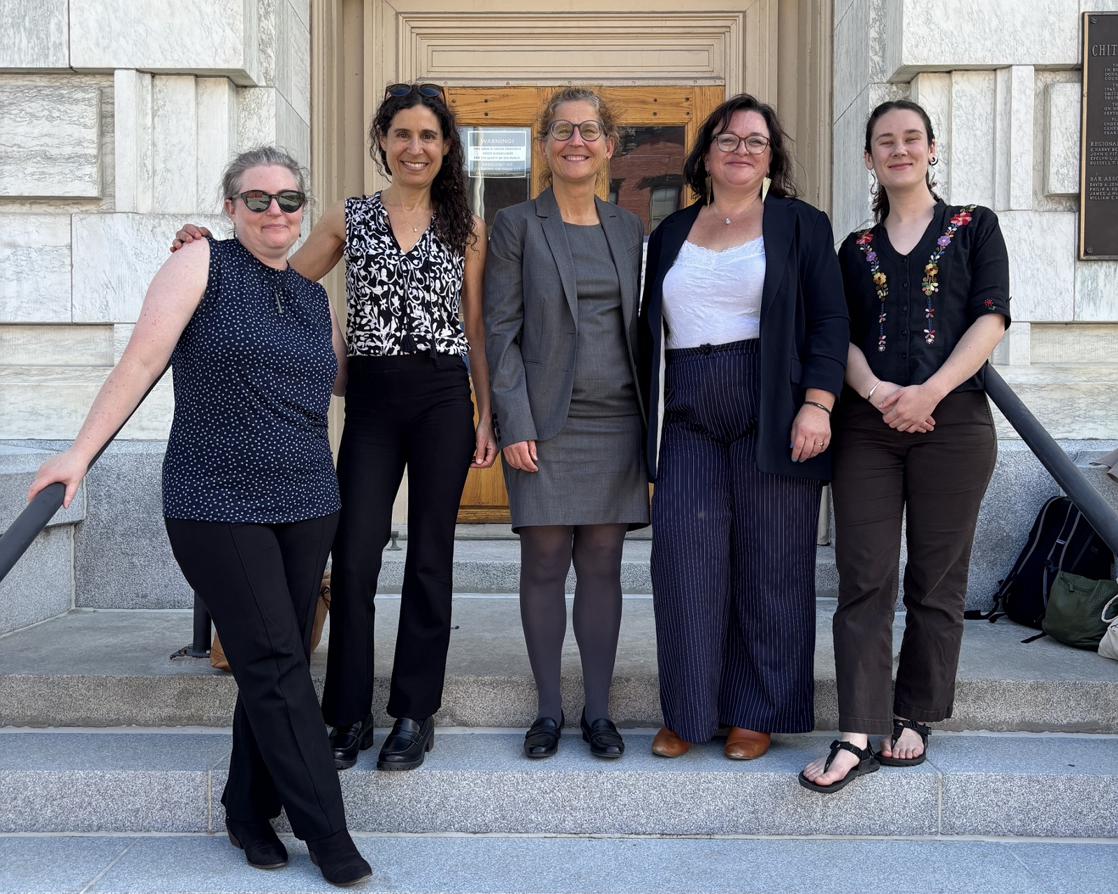 5 women stand on steps of courthouse
